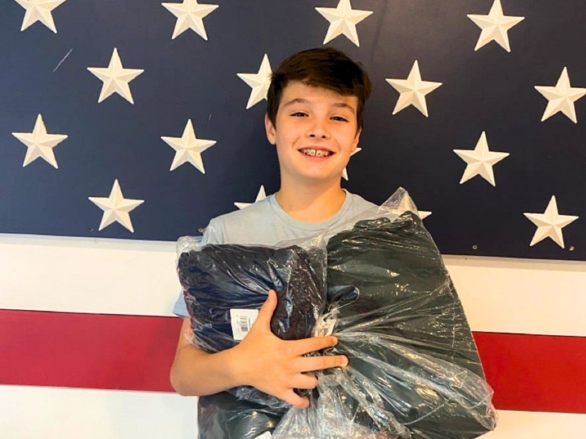 Young volunteer Grayson holds donated winter clothing for veterans during Operation: Veteran Connect’s Warmth for the Winter Campaign.